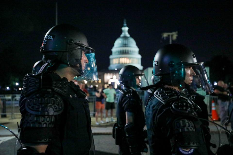 A group of protesters dressed in all black move instruction barrels in front of the police line, making their way towards the Supreme Court in Washington DC.