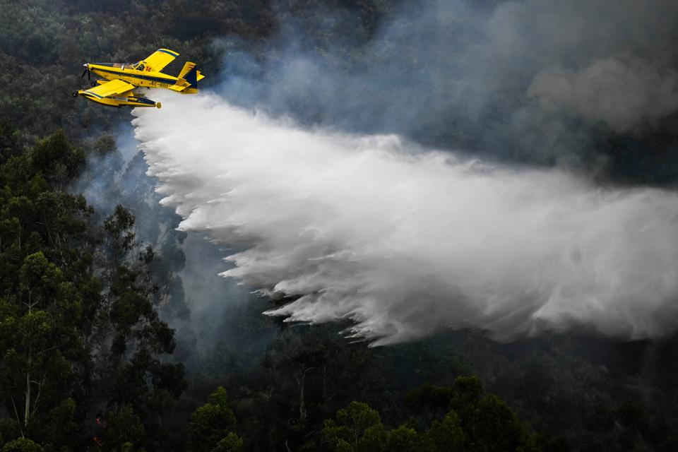 A fire fighting aircraft Air Tractor AT-802F Fire Boss drops water on a wildfire near Bustelo, east of Amarante, north of Portugal.