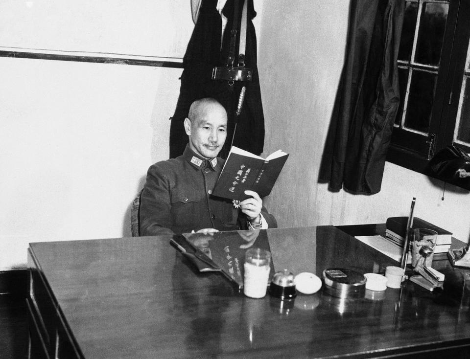 General Chiang Kai-shek, seated at his desk in his office, reading a copy of his new book China's Destiny, which was translated into English in 1943.