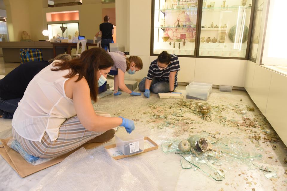 The Museum team, conservator and student volunteers retrieve fragments of broken glass vessels from amongst the shattered glass from the display case and nearby windows, at the Archaeological Museum, AUB.