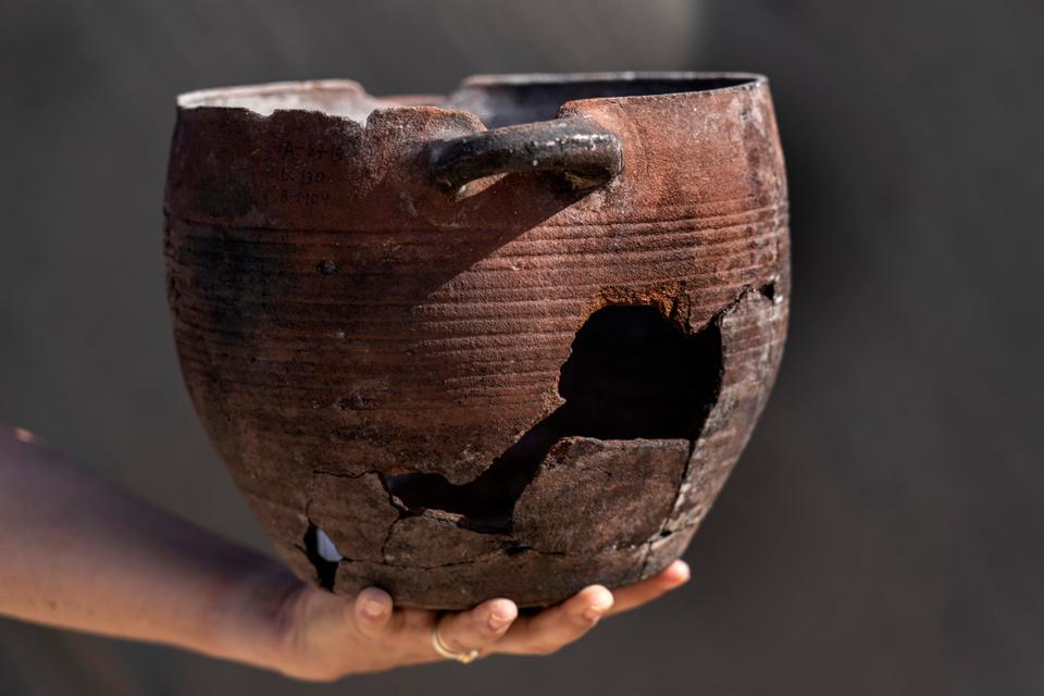 A woman holds a vessel from a 1,200-year-old rural estate discovered during excavations by the Israel Antiquities Authority during expansion of the town of Rahat, Israel, Aug. 23, 2022.
