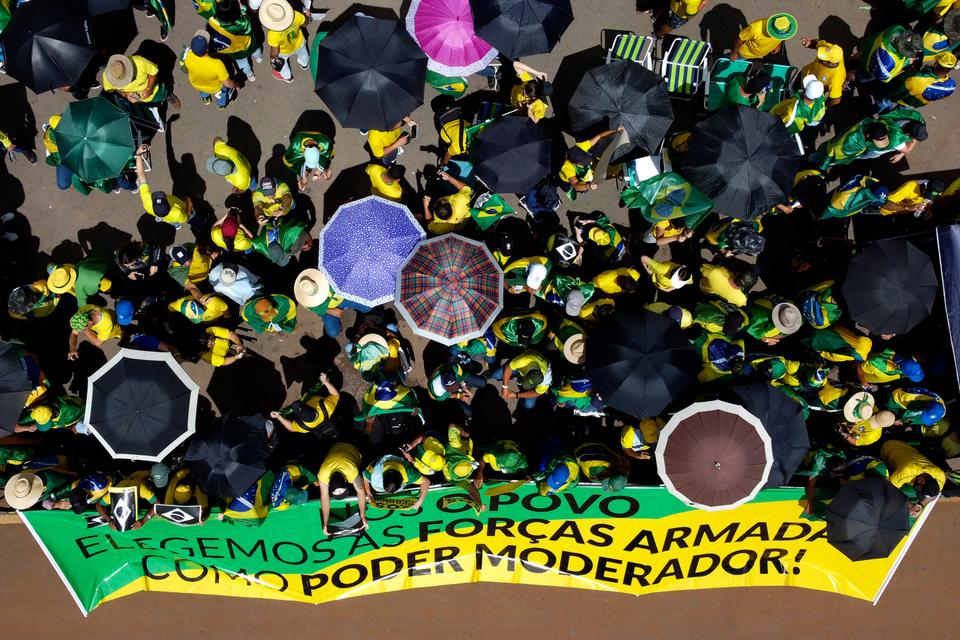 Supporters of Brazilian President Jair Bolsonaro stand behind a banner that reads in Portuguese “We, the people, elect the Armed Forces as a moderating power” as they protest against Bolsonaro’s run-off election loss outside Army headquarters in Brasilia, Brazil, Tuesday, November 15, 2022.