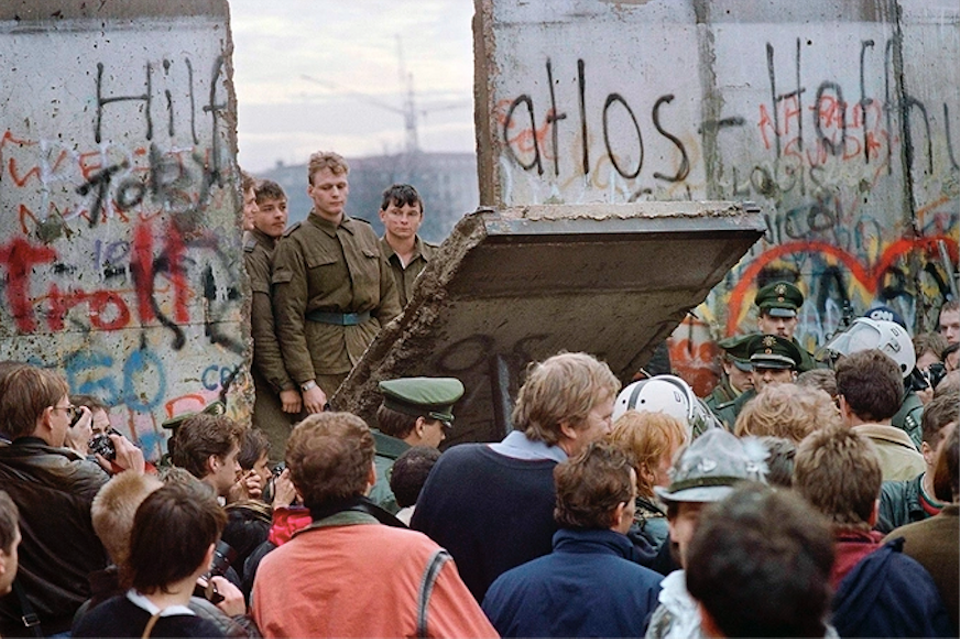 West Berliners crowd in front of the Berlin Wall in November 1989 as they watch East German guards demolish a section of the barrier to open a crossing point between East and West Berlin.