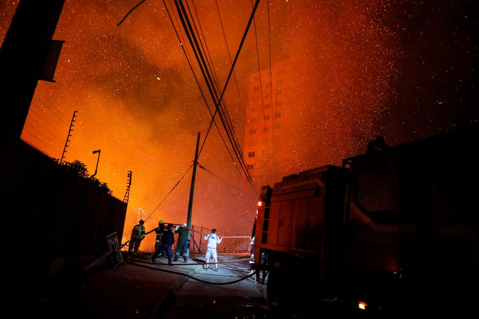 Firefighters work as a forest fire affects the hills of Vina del Mar, where hundreds of houses are located.