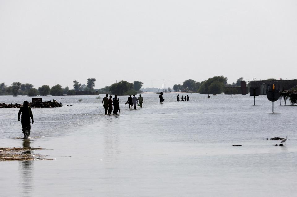 People walk amid rising flood waters on the Indus highway, following rains and floods during the monsoon season in Mehar, Pakistan August 31, 2022.