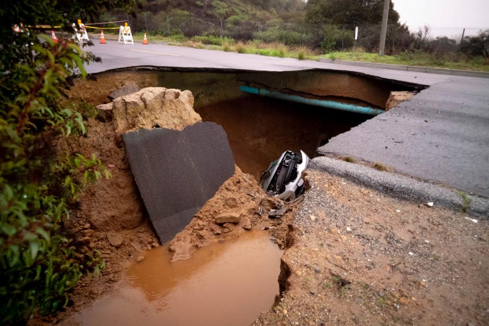 Cars remain in a large sinkhole along Iverson Road in Chatsworth in California.