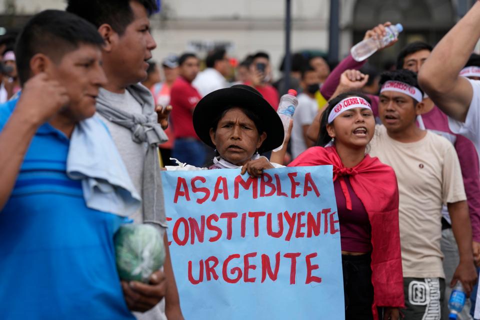 A woman holds a sign that reads in Spanish 