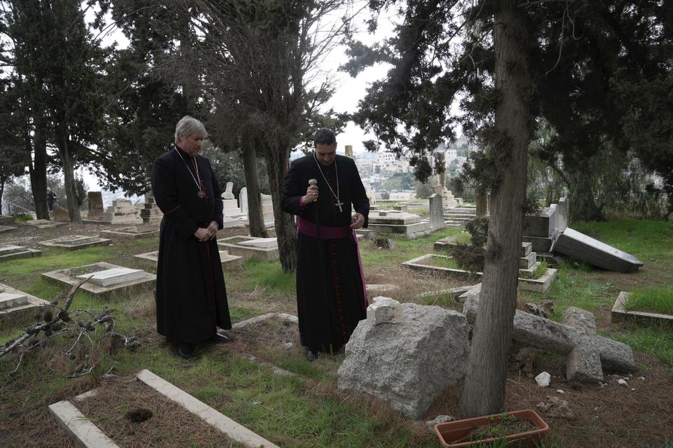 Hosam Naoum, a Palestinian Anglican bishop, right, stands with a colleague where vandals desecrated more than 30 graves at a historic Protestant Cemetery on Mount Zion in occupied East Jerusalem, Wednesday, Jan. 4, 2023.