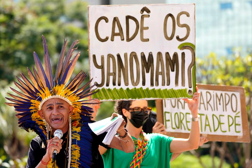 Indigenous leader Nando Potiguara speaks in front of a poster that says in Portuguese