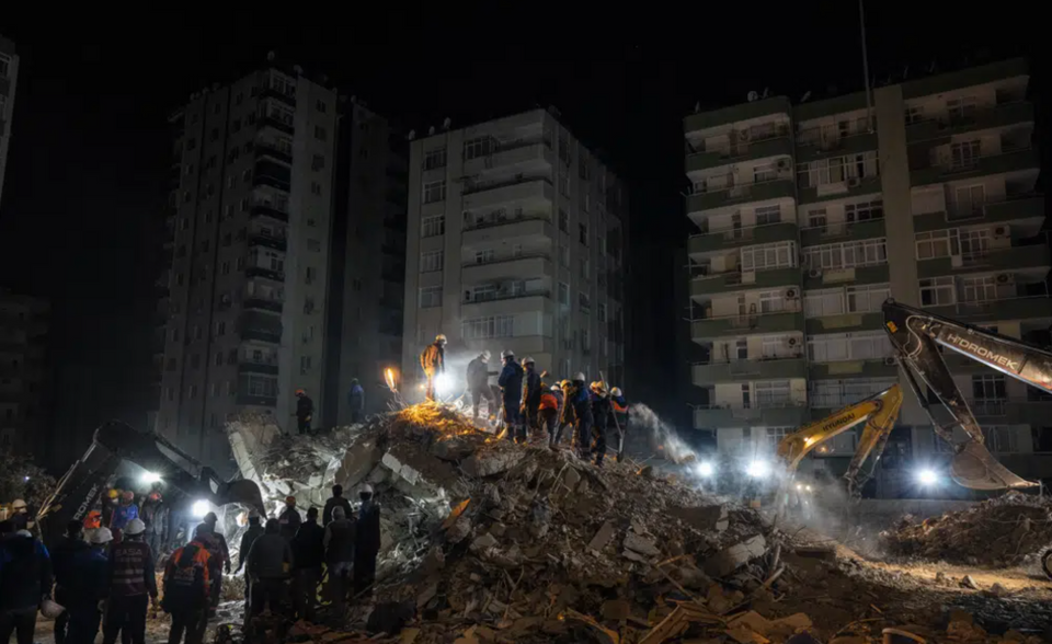 Rescue workers search for bodies and earthquake survivors on a collapsed building in southern Adana province.