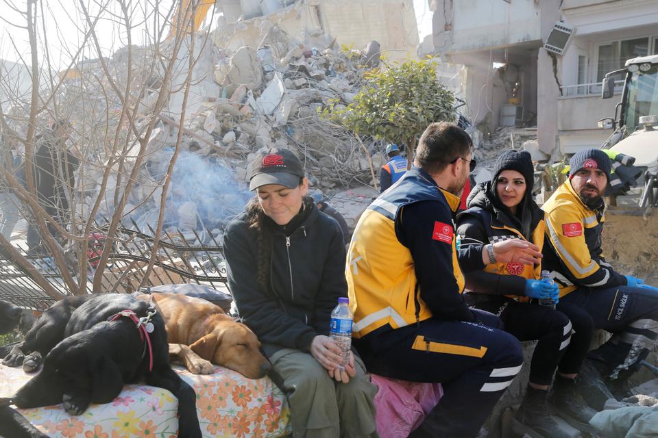 Rescuers sit next to their dogs in Hatay on Monday in the aftermath of the deadly disaster.