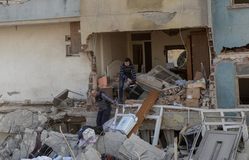 Residents of Hatay province try to take their belongings out of their destroyed apartment in the aftermath of the deadly February 6 earthquakes.