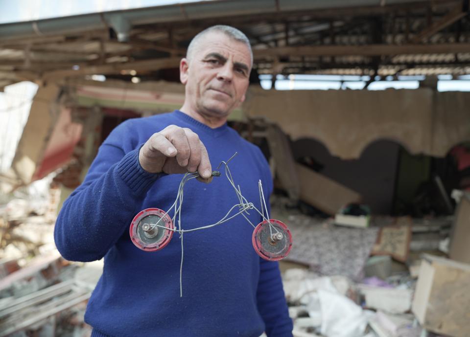 Dogan holds a model of an iron bicycle made by his youngest daughter that he managed to unearth from the rubble.