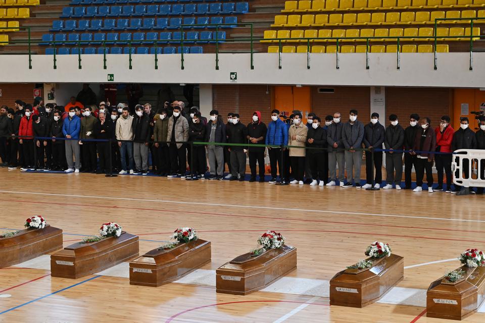 Mourners pray by the coffins of the victims in the sports hall of Crotone.