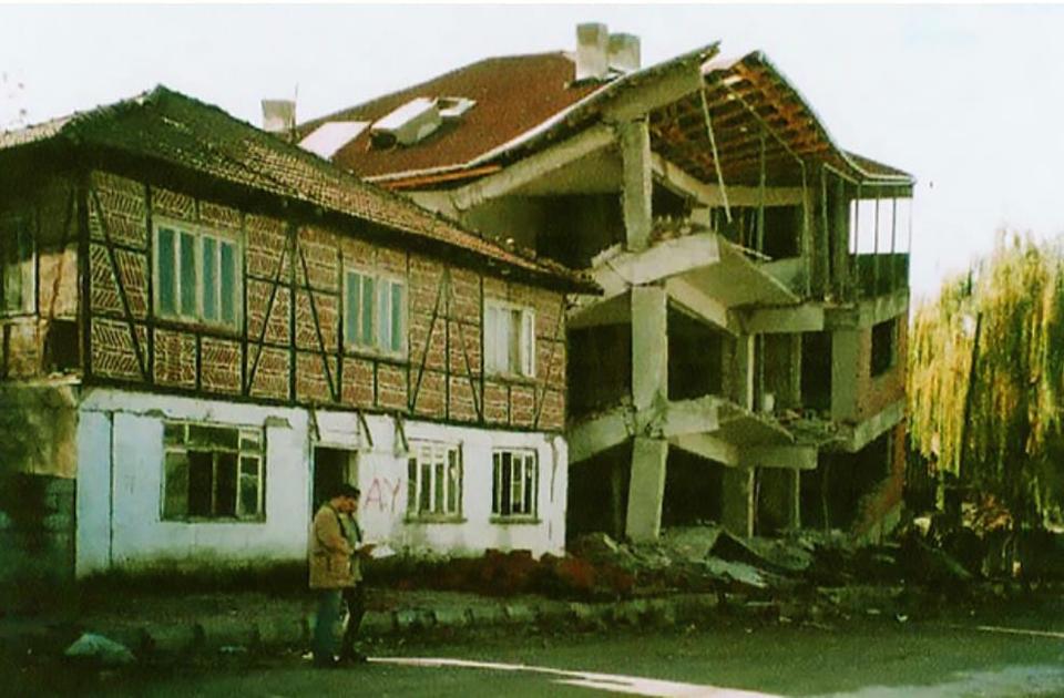 View of traditional Turkish house with very little damage next to collapsed four-story reinforced concrete building after the 1999 Duzce earthquake.