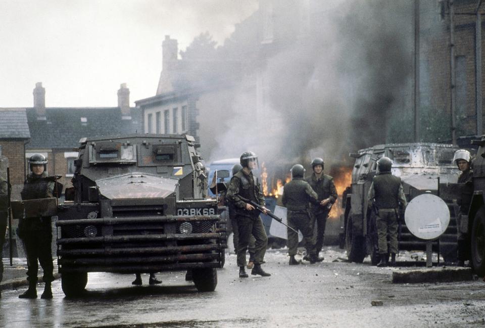 British troops, with their armoured personnel carriers, surround a blazing barricade near the Andersonstown Police Station in Belfast, Northern Ireland in 1979.
