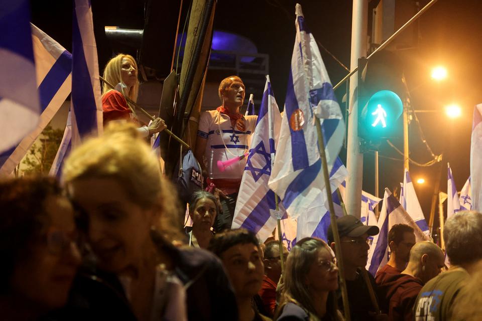 People hold Israeli flags during a demonstration against Israeli Prime Minister Benjamin Netanyahu.