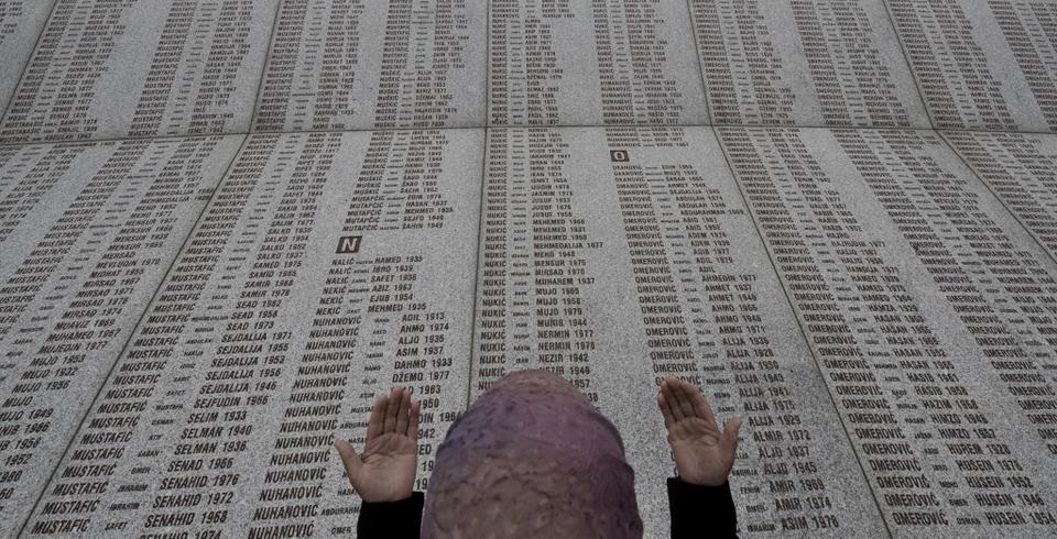 A Bosnian Muslim woman prays at the memorial wall with the names of the victims at the Potocari Memorial Center near Srebrenica on July 22, 2008..