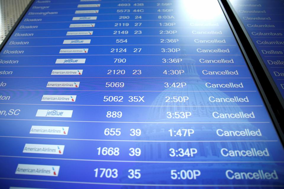 A flight information board shows cancelled flights as a storm bringing high winds passes over Reagan National Airport in Washington.