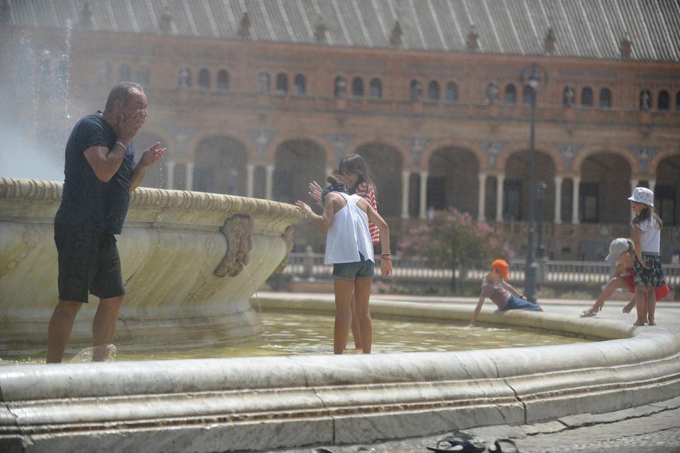 People refresh themselves in a fountain at Plaza de Espana, on a hot summer day in Sevilla, Spain on August 1, 2018.