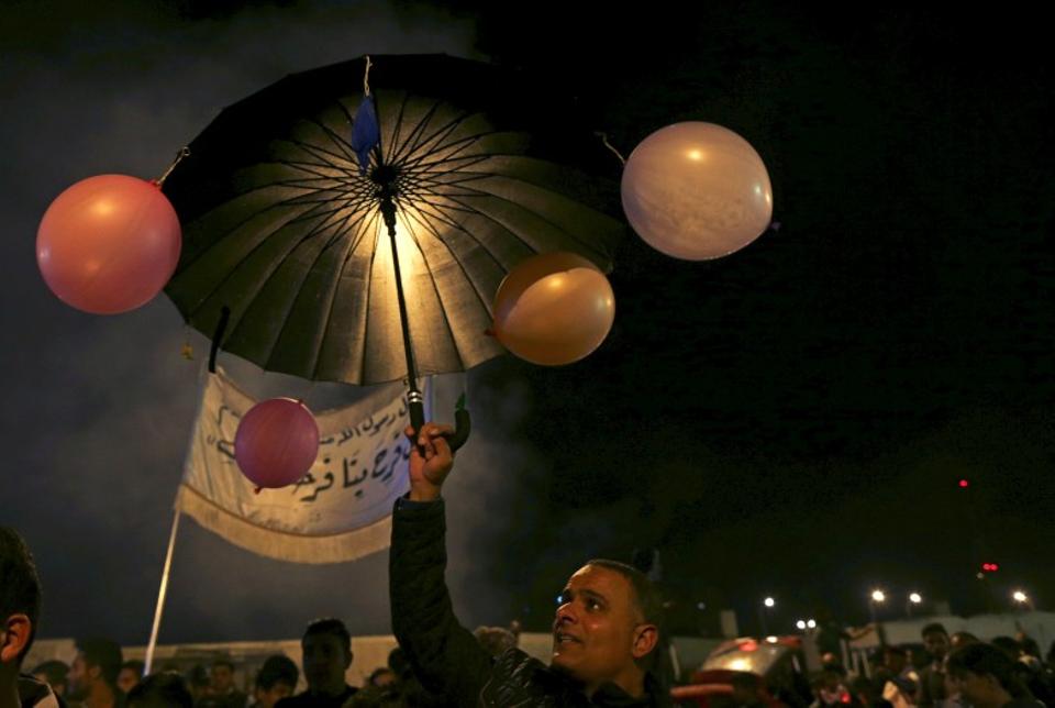 Seorang pria membawa payung yang dihiasi balon selama prosesi merayakan Maulid di Benghazi, Libya.