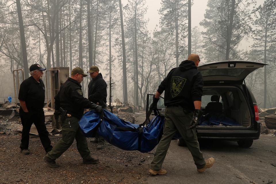 Yuba and Butte County Sheriff deputies carry a body bag with a deceased victim during the Camp fire in Paradise, California, US on November 10, 2018.