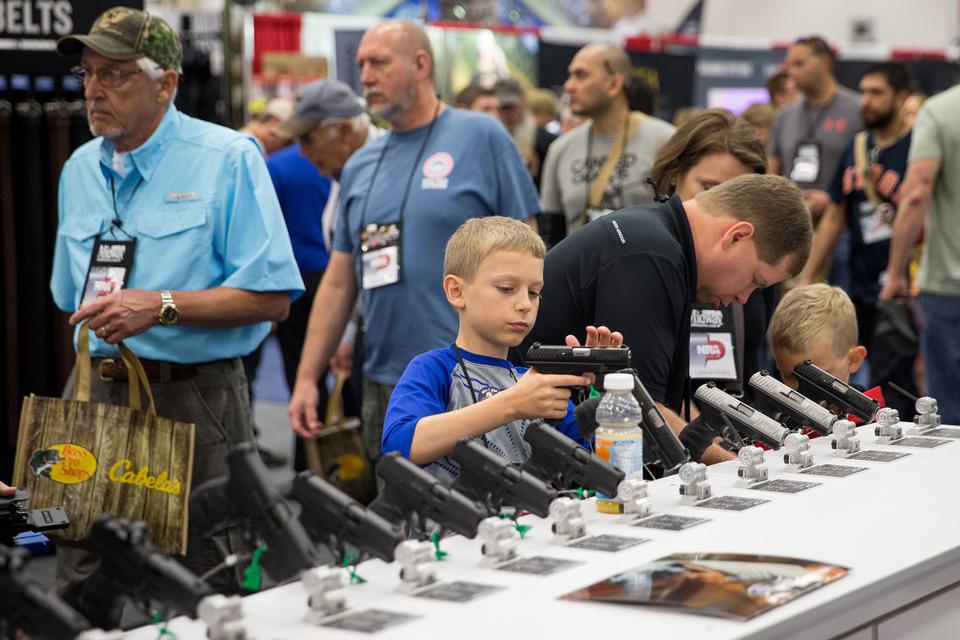 A young boy inspects a firearm in an exhibit hall at the NRA's annual convention on May 5, 2018 in Dallas.
