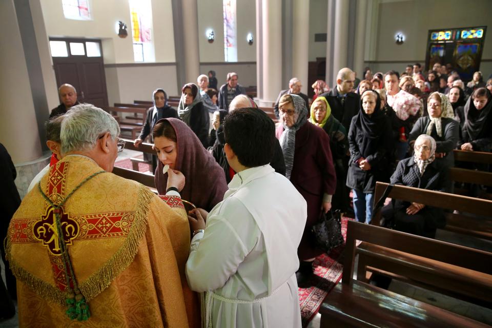 An Iranian takes communion from archbishop Ramzi Garmou, left, during Christmas Mass at Saint Joseph Chaldean- Assyrian Catholic church, in Tehran, Iran.