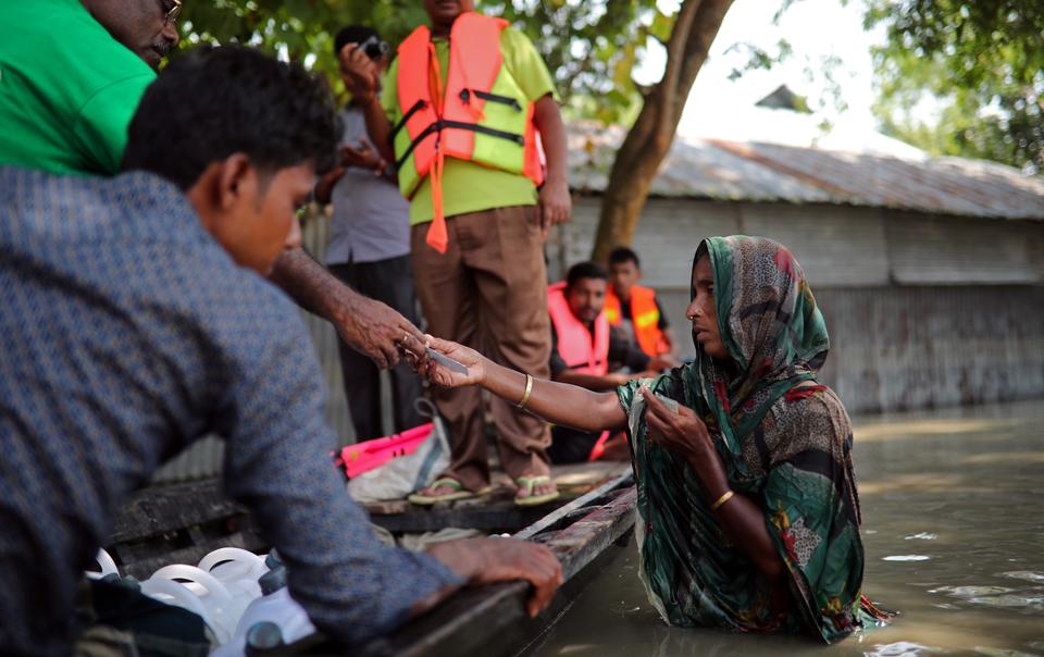 Flood-affected people receive water-purifying tablets from volunteers in Jamalpur, Bangladesh, July 21, 2019