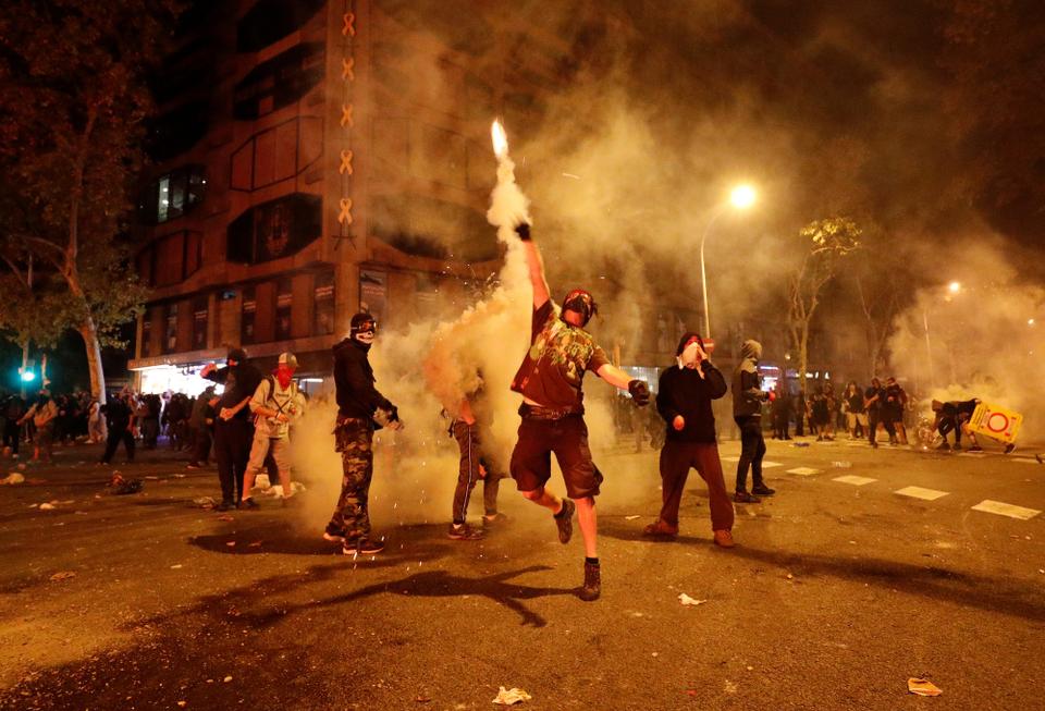 A Catalan demonstrator throws a tear gas canister back to the riot police during Catalonia's general strike in Barcelona, Spain, October 18, 2019.