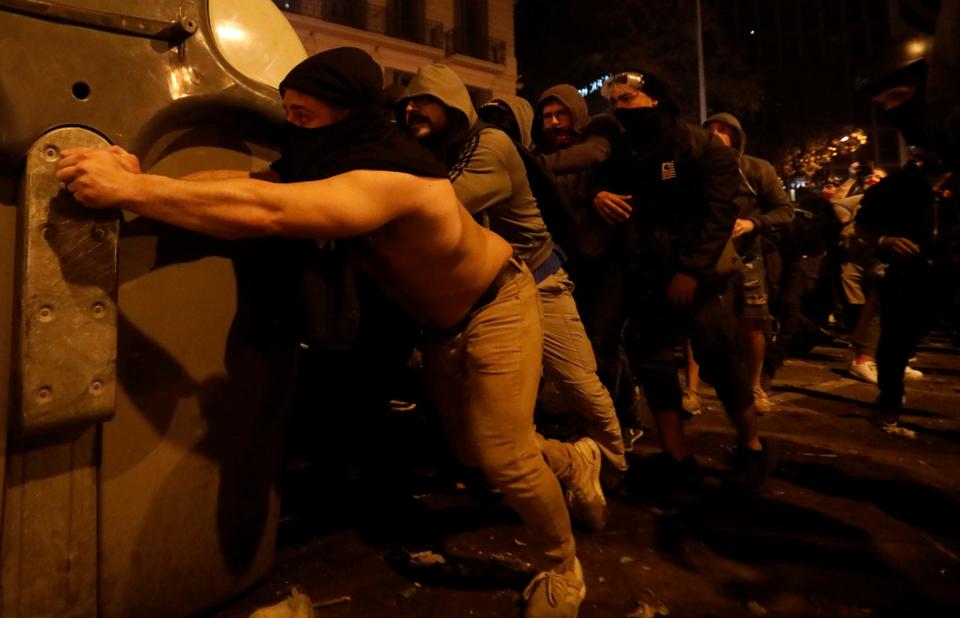 Catalan demonstrators push a dumpster as they take cover behind it during Catalonia's general strike, in Barcelona, Spain, October 18, 2019.