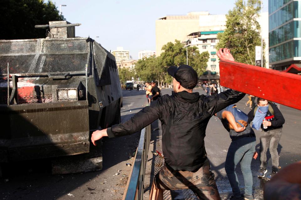 A demonstrator clashes with riot police during a protest against the increase in the subway ticket prices in Santiago, Chile, October 18, 2019