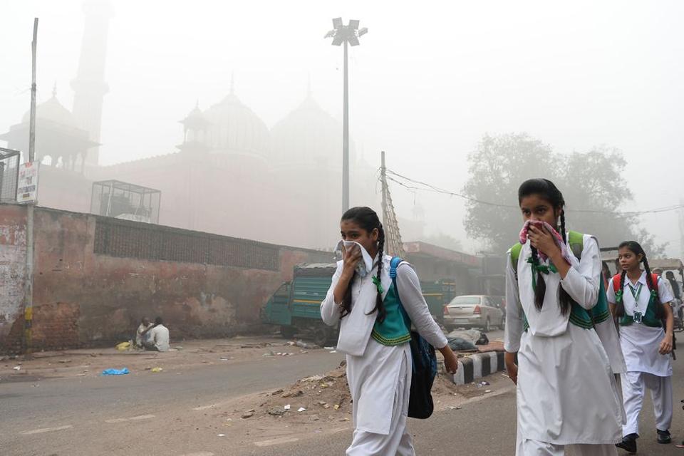 Indian schoolchildren cover their faces as they walk to school amid heavy smog.