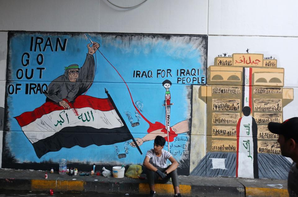 In this file photo from November 8, 2019, an Iraqi protester rests in front of a mural in Baghdad's Tahrir Square as the Iraqi capital braces for another day of anti-government demonstrations.