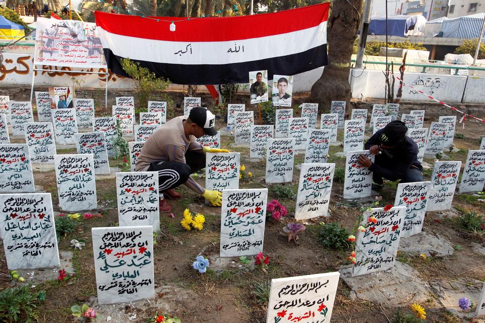 Iraqi demonstrators clean a symbolic cemetery of those who were killed at anti-government protests at Tahrir Square, in Baghdad