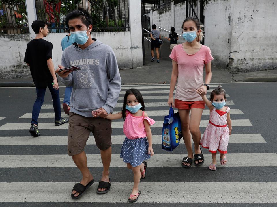 A family wearing protective masks crosses a street in Mandaluyong, east of Manila, Philippines on Sunday, Feb. 2, 2020.