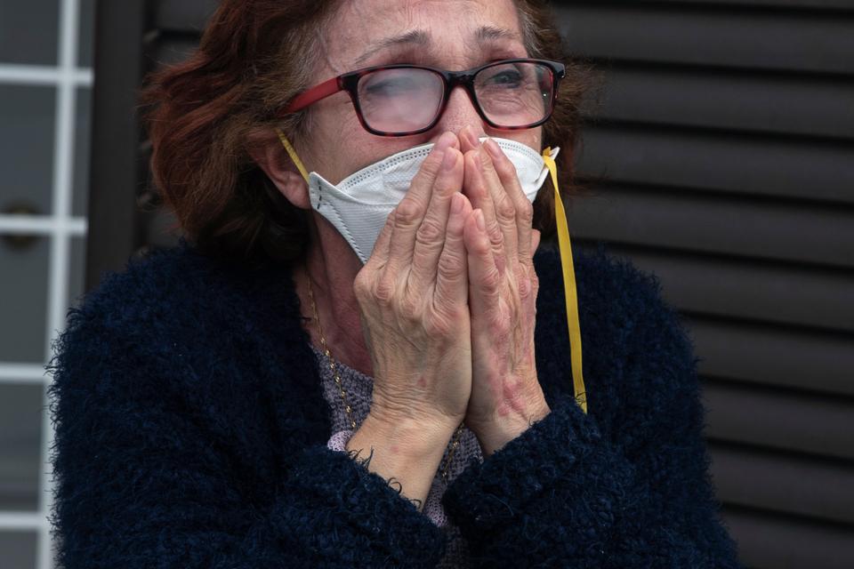 A woman wearing a face mask cries during her granddaughter Lucia's 12th birthday celebration while her parents are working, at her home during the lockdown to combat the spread of coronavirus in Grinon, Spain, Friday, April 17, 2020.