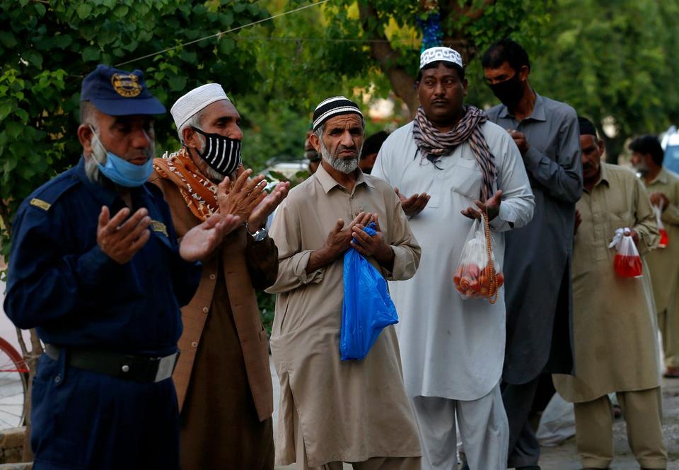 People pray before receiving free food for breaking their fast on the second day of Ramadan, in Islamabad, Pakistan. Sunday, April 26, 2020. Millions have started the Muslim fasting month Ramadan, the holiest month on the Islamic calendar, under the coronavirus lockdown or strict social restrictions.