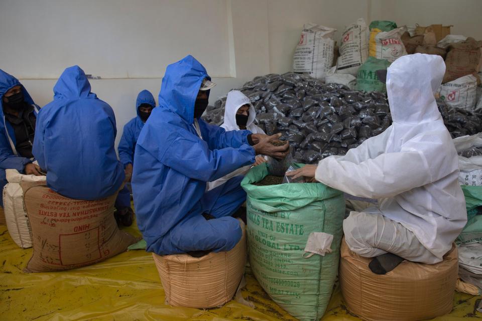 Kashmiri men employed by government pack tea bags for distribution among needy people inside a temporary storage in Srinagar, Indian controlled Kashmir, Tuesday, April 21, 2020.