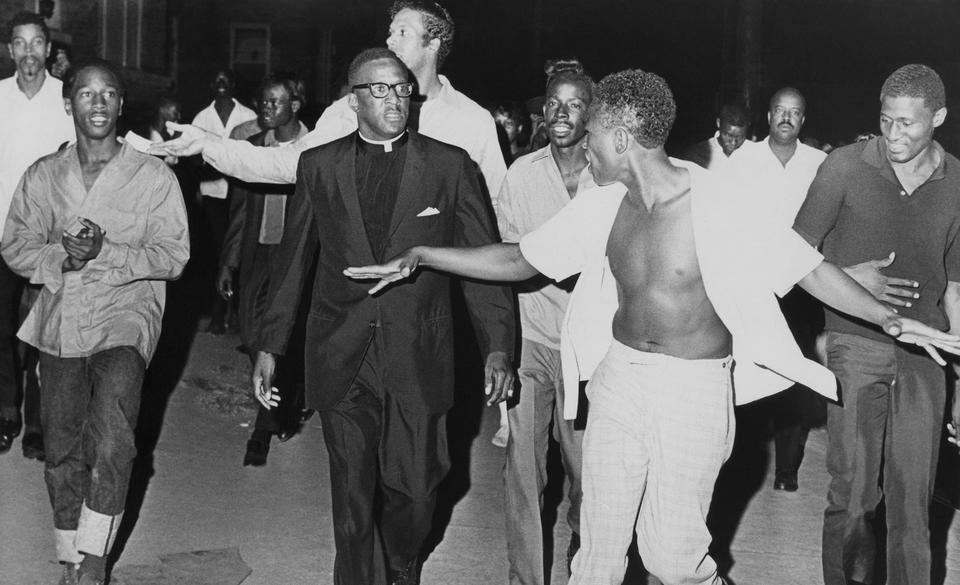 An unidentified minister leads a crowd of taunting blacks on a block-long march in a predominantly black section of northeast Atlanta, Ga., Sept. 11, 1966. Sporadic violence broke out in the area, where riots broke out the day after a black teenager was killed and two other persons wounded.