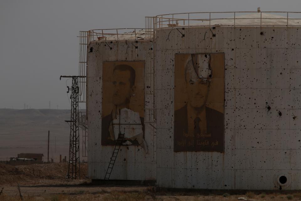 Damaged pictures of Syria's regime leader Bashar al-Assad and his father, former president Hafez al-Assad are seen on storage tanks in Deir al-Zor, Syria September 20, 2017.