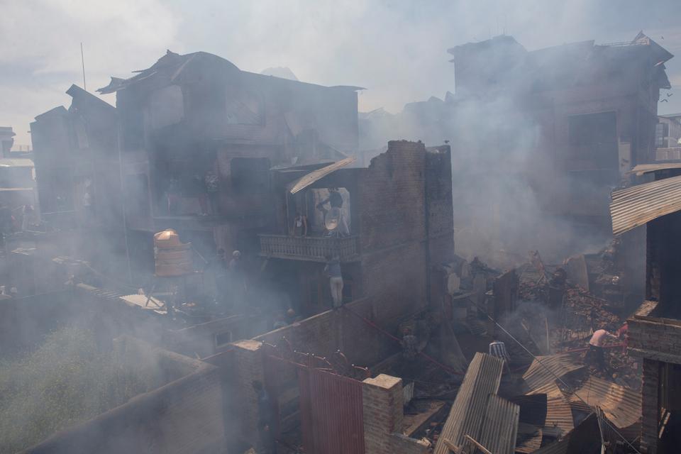 Kashmiri men douse the fire in a neighbourhood which was allegedly destroyed by the Indian police and paramilitary forces in a gun-battle in Srinagar, Indian controlled Kashmir, Tuesday, May 19, 2020.