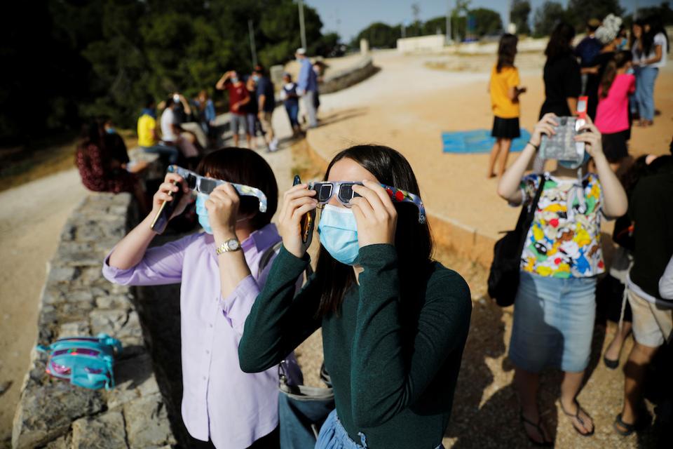 Women use protective glasses to observe a partial solar eclipse from Mount Scopus in Jerusalem.