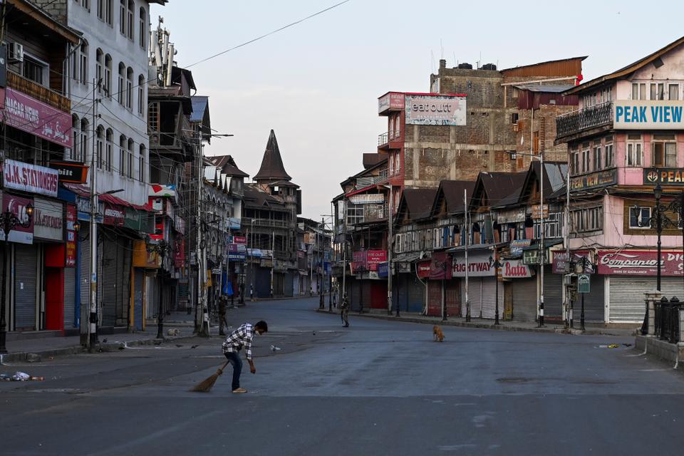 A municipal worker cleans a road before curfewed hours in Srinagar on August 4, 2020.