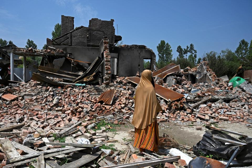 In this picture, taken on July 30, 2020, a woman inspects the rubble of houses belonging to relatives. The buildings were blasted by mortars fired by Indian soldiers during a firefight with rebels, at Sopore north of Srinagar.