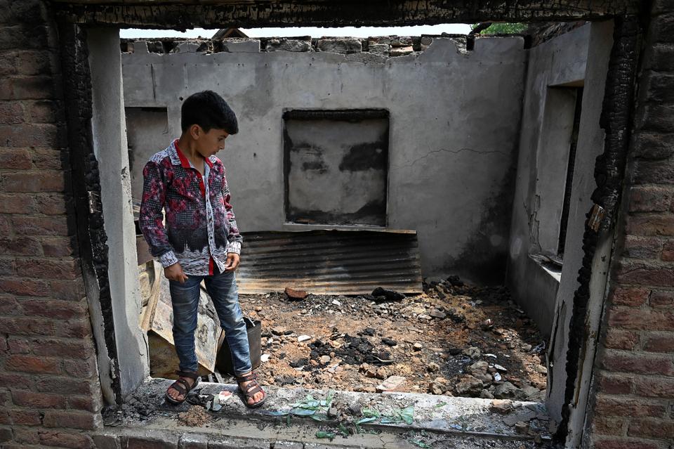 In this picture, taken on July 30, 2020, a boy looks inside houses decimated by mortars fired by Indian soldiers during the firefight with rebels, in Sopore.