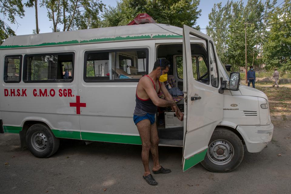 Jameel Ahmed, a Kashmiri ambulance driver disinfects himself after carrying the body of a paramilitary officer who died of COVID-19 at a crematorium in Srinagar, Indian-controlled Kashmir, Tuesday, July 14, 2020.