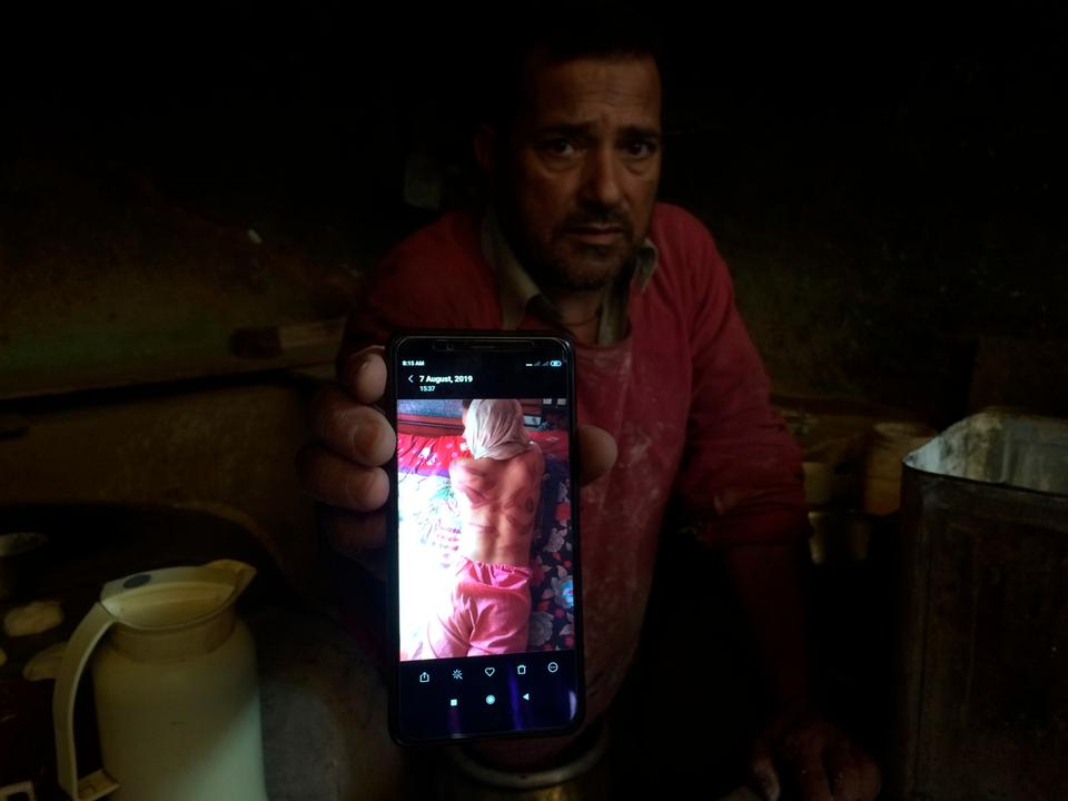 In this August 26, 2019, photo, a Kashmiri baker, Sonaullah Sofi, shows a photograph of his son after he was allegedly tortured by Indian army soldiers at their bakery in the southern village of Parigam, Indian-controlled Kashmir.