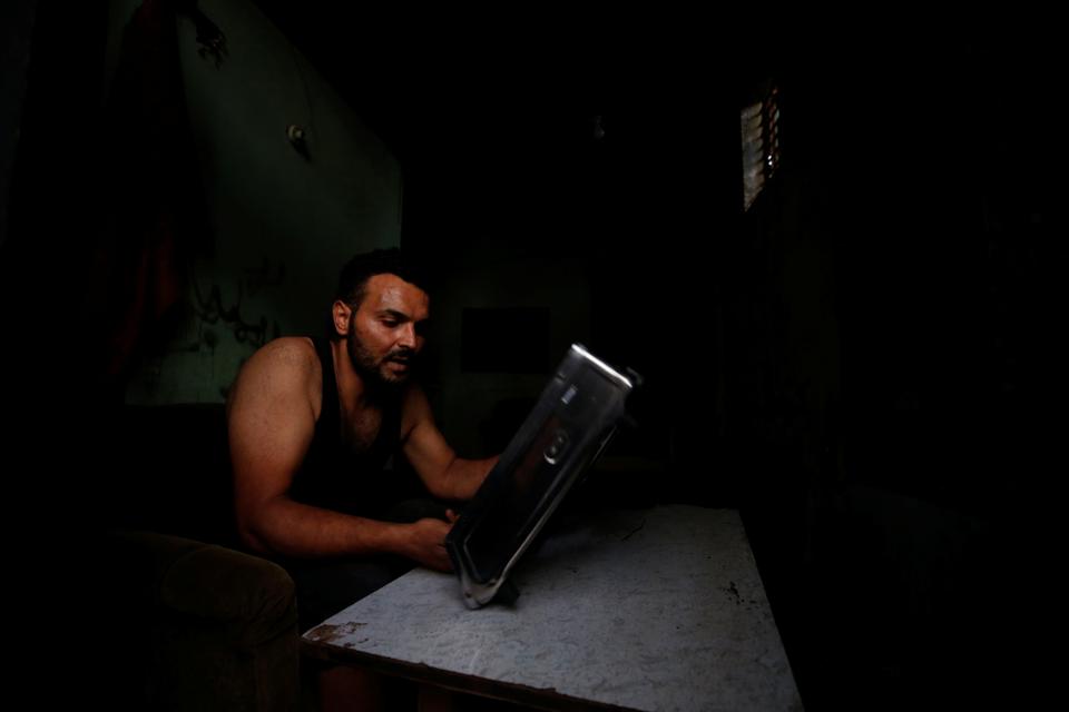 A Palestinian man fixes a stove in his workshop that is illuminated a battery-powered LED light during a power cut after Gaza's lone power plant shut down amid tension with Israel, at the Beach refugee camp in Gaza City August 18, 2020.