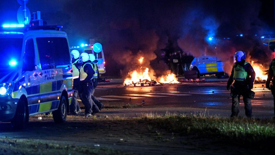 Police officers walk near the burning tyres and pallets during a riot in the Rosengard neighbourhood of Malmo, Sweden August 28, 2020.
